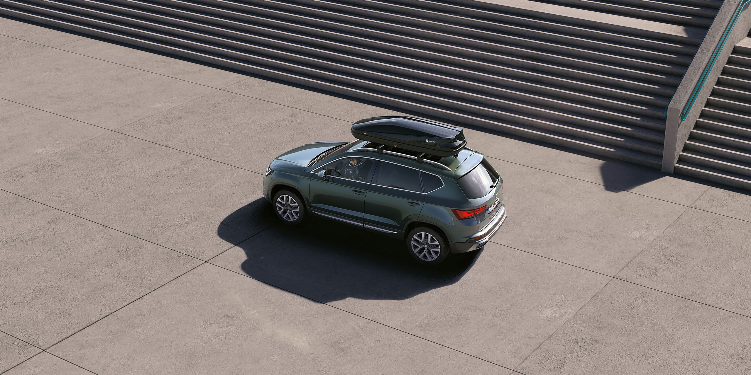 Ein grüner SEAT Ateca mit einer schwarzen Dachbox.