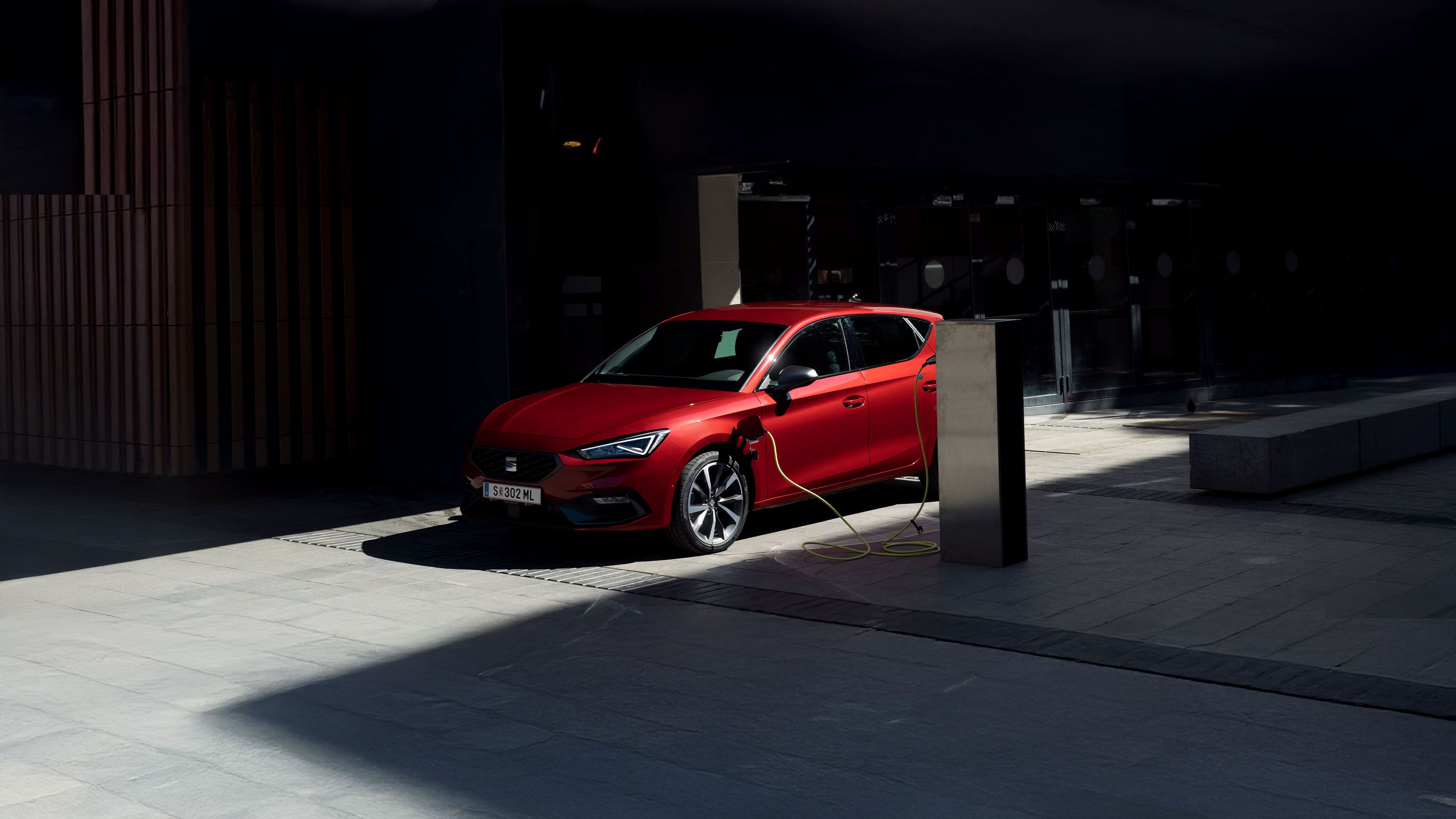 Ein roter SEAT Leon wird an einer Ladesäule geladen.
