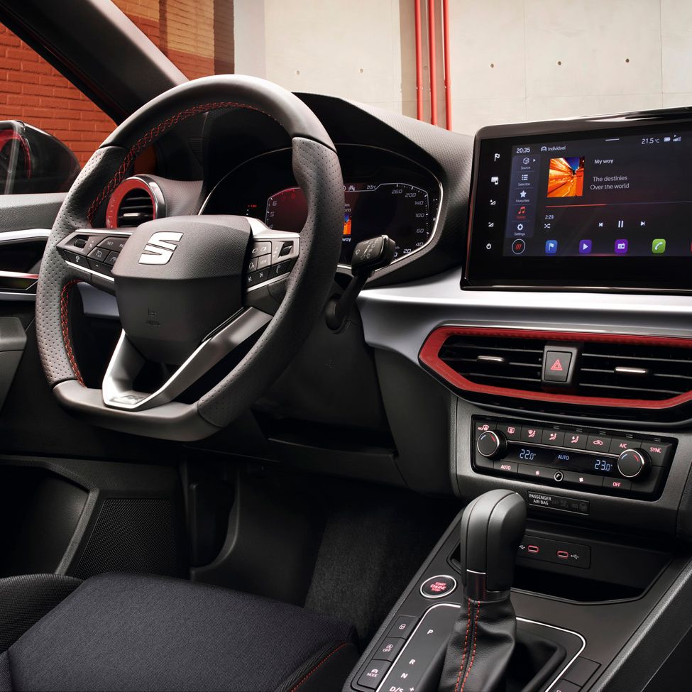 Innenansicht mit Fokus auf das Lenkrad, das digitale Cockpit und das Display, das gerade Musik abspielt