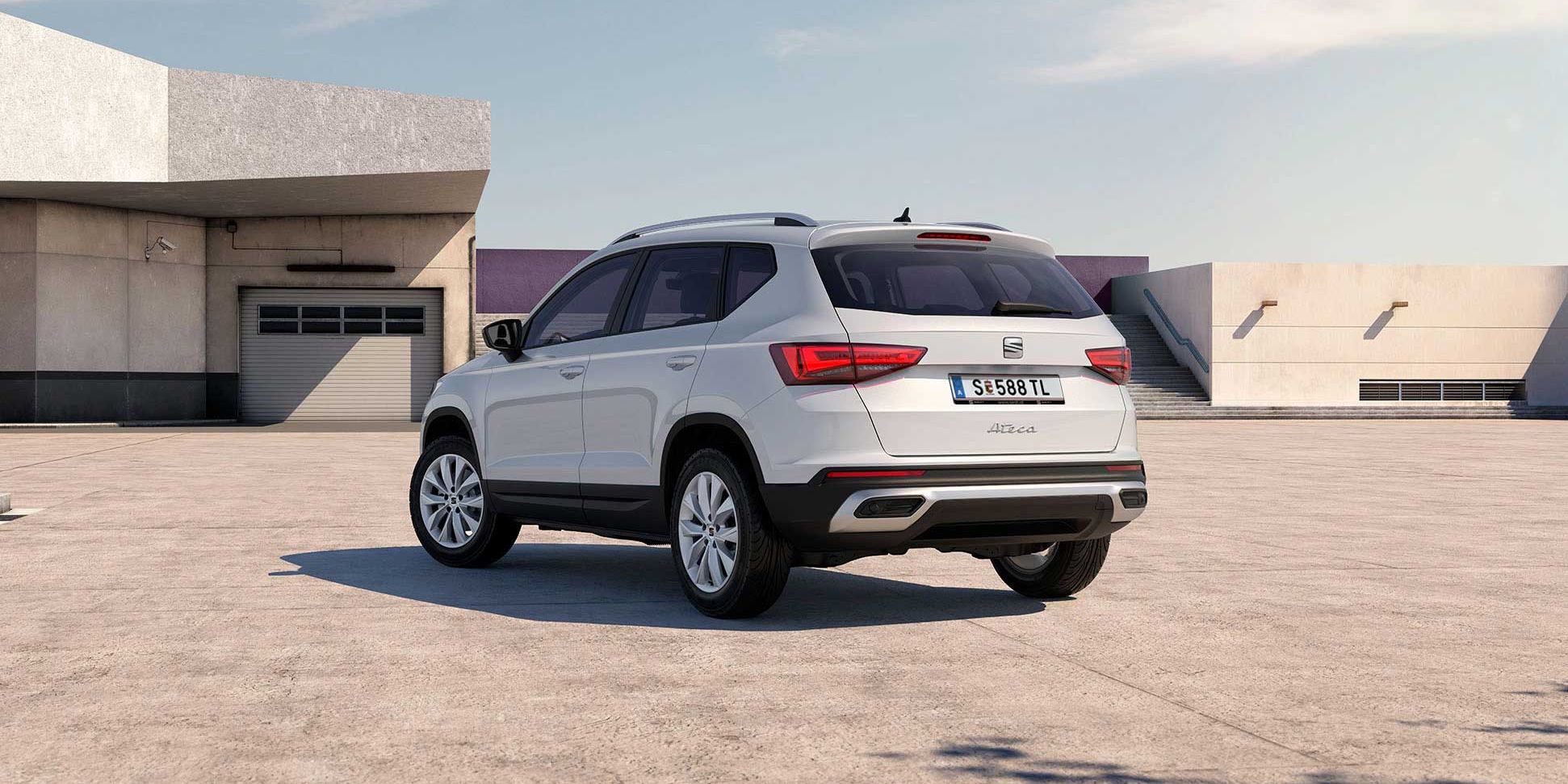 Ein weißer SEAT Ateca steht auf einem Parkplatz vor einem Gebäude.