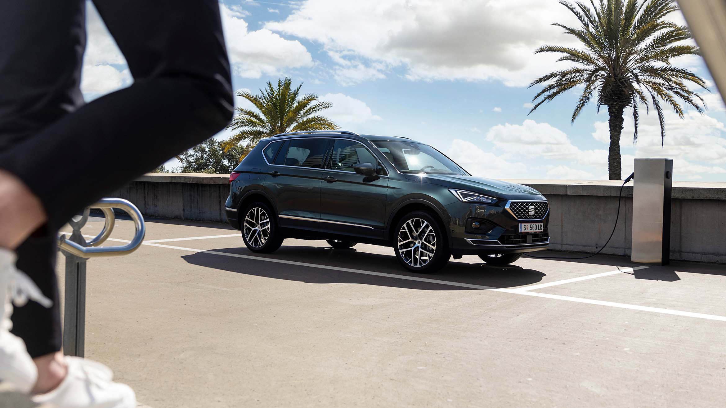 Eine Person geht, während des Ladevorgangs, zum neuen SEAT Tarraco XPERIENCE 