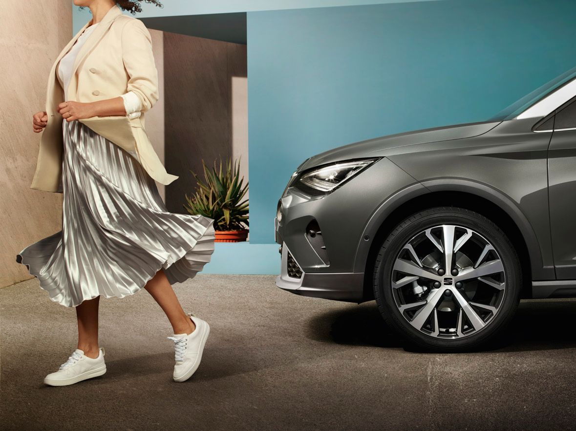 Nahaufnahme eines SEAT Arona, bei der die Felge im Mittelpunkt steht, während eine Frau vom Auto weggeht