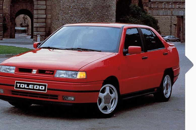 Ein roter SEAT Toledo von 1991 in Fahrt durch eine Stadt.
