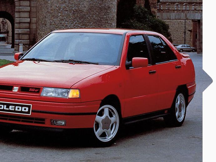Ein roter SEAT Toledo von 1991 in Fahrt durch eine Stadt.