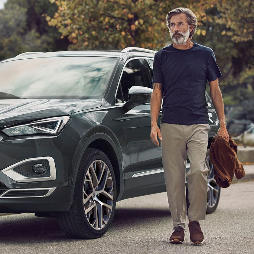Ein Mann bewegt sich von einem grauen SEAT Tarraco fort.