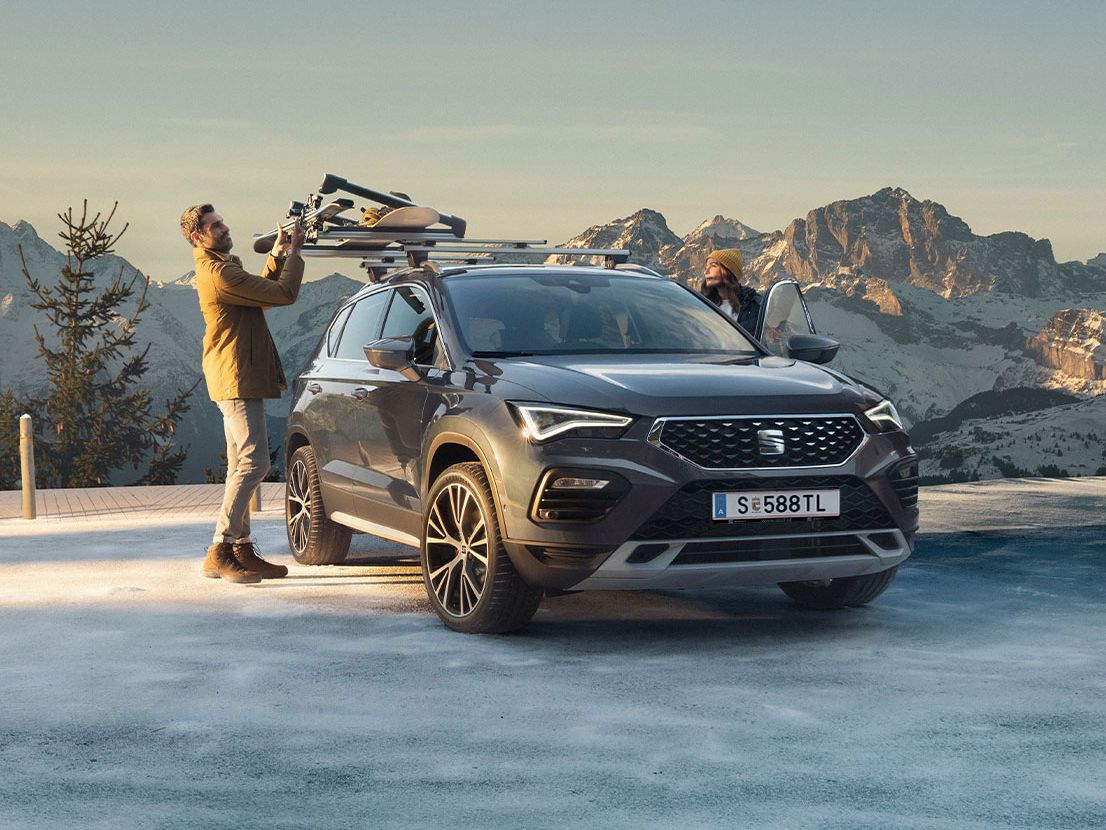 SEAT Ateca am Berg mit Mann beim Ski anbringen am Autodach