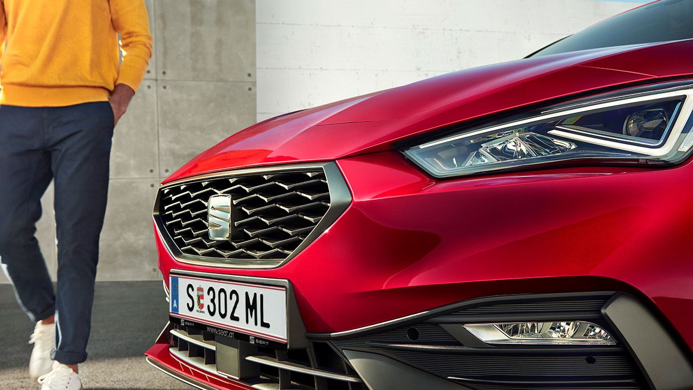 Detailansicht eines roten SEAT Leon 5-Türer, ein Mann steht links neben dem Fahrzeug