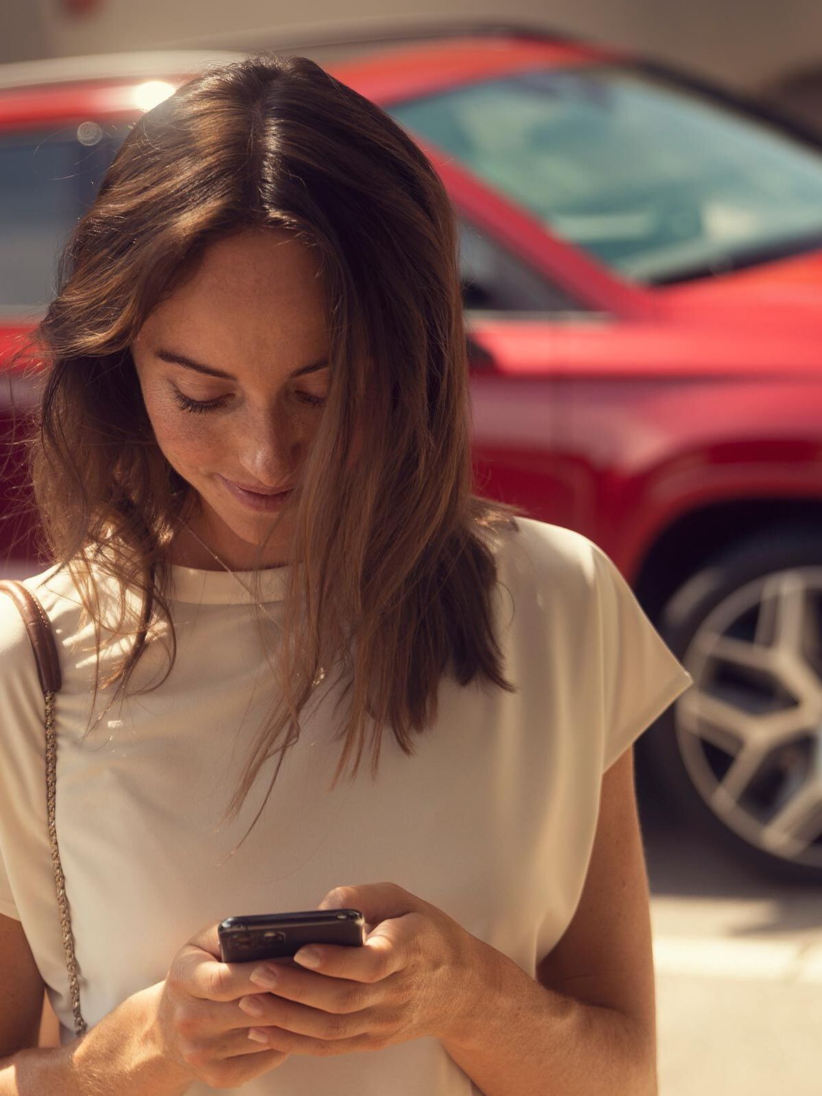 Eine Frau hält ihr Smartphone in der Hand und nutzt gerade SEAT Connect.