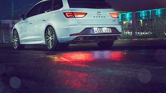 Heckansicht eines weißen SEAT CUPRA  in Fahrt bei Nacht.