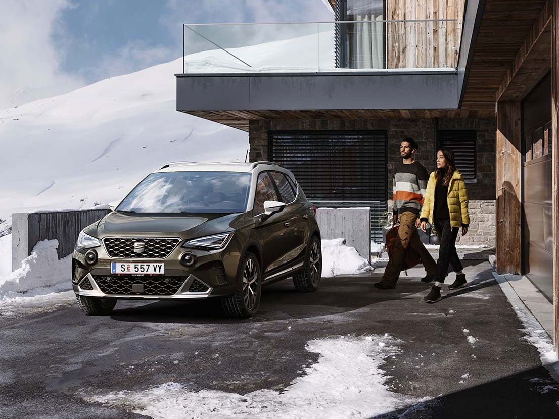 Ein Mann und eine Frau spazieren gemeinsam in Richtung des geparkten SEAT Arona