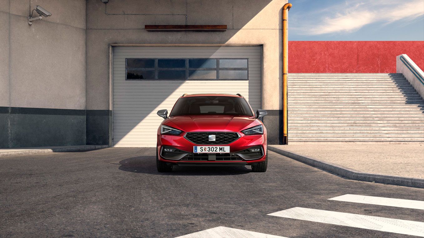 Frontansicht eines roten SEAT Leon SP Kombi, der vor einer Garage parkt.