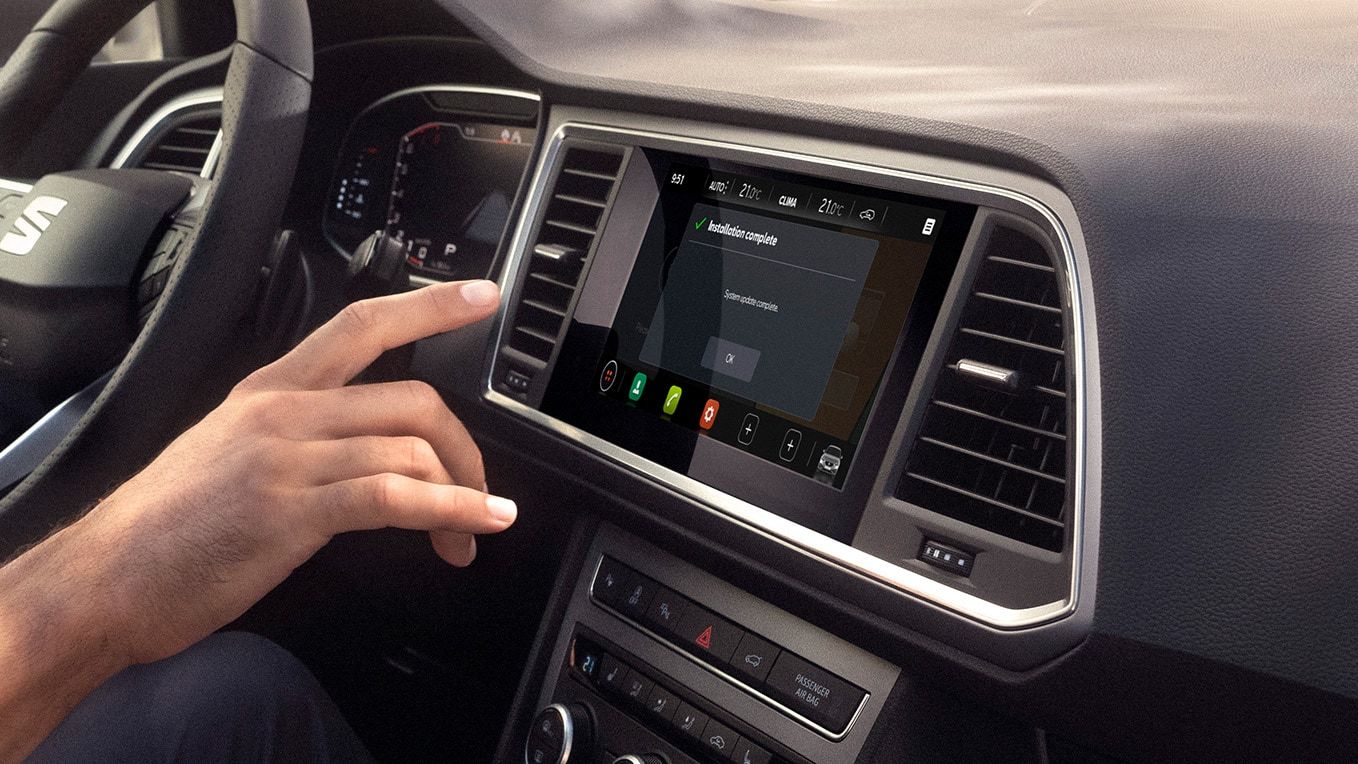 Eine Hand greift zum Navi System im SEAT Ateca