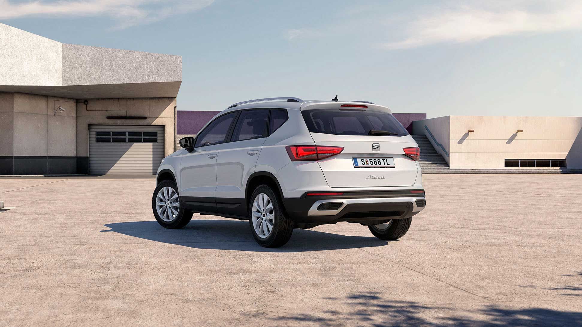 Ein weißer SEAT Ateca steht auf einem Parkplatz vor einem Gebäude.