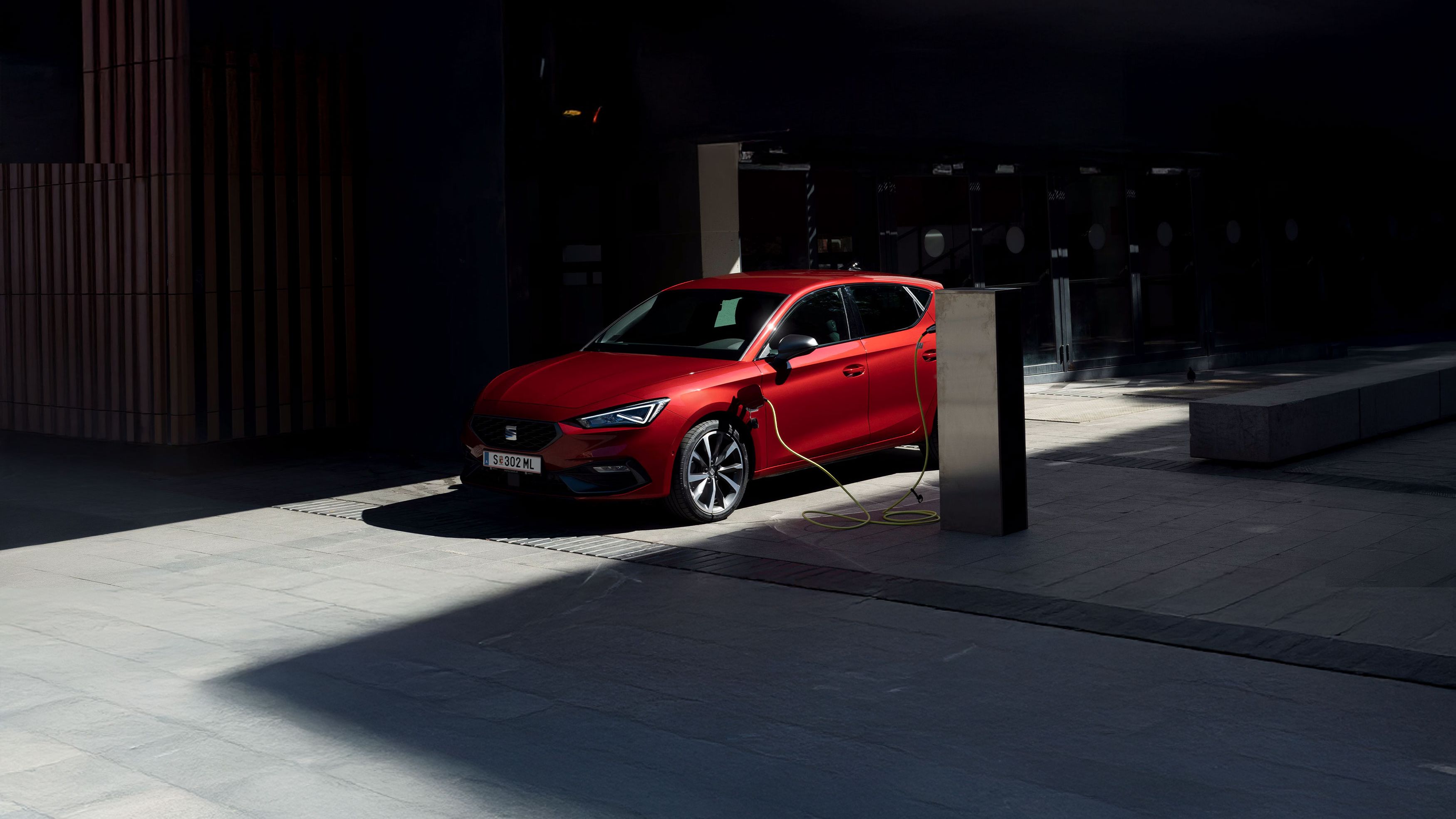 Ein roter SEAT Leon wird an einer Ladesäule geladen.