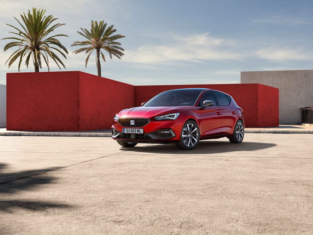 Roter SEAT Leon 5-Türer FR parkt vor einem roten Gebäude