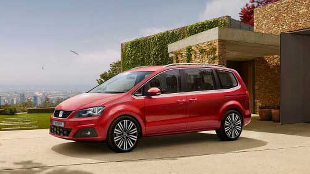 Seitenansicht eines roten SEAT Alhambra parkend vor einem Gebäude.