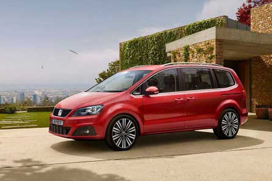 Seitenansicht eines roten SEAT Alhambra parkend vor einem Gebäude.