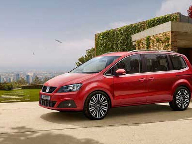 Seitenansicht eines roten SEAT Alhambra parkend vor einem Gebäude.