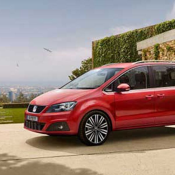 Seitenansicht eines roten SEAT Alhambra parkend vor einem Gebäude.