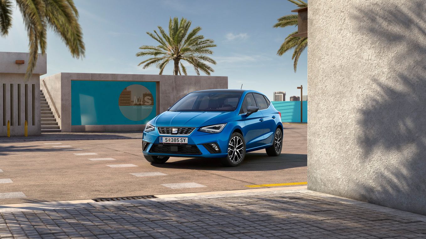 Ein blauer SEAT Ibiza vor einem Gebäude mit Palmen im Hintergrund.