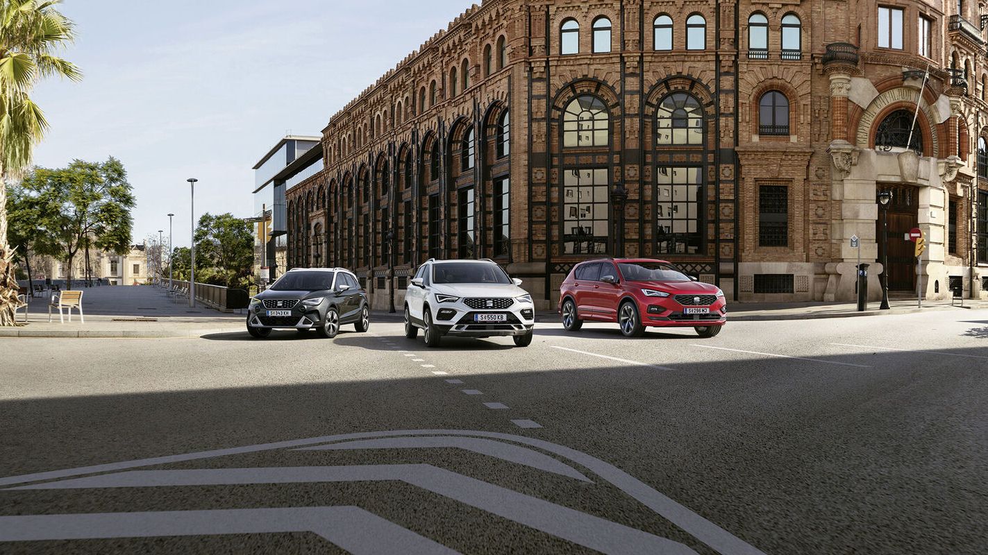 Ein SEAT Arona, ein Tarraco und ein Ateca in Fahrt auf einer Straße.