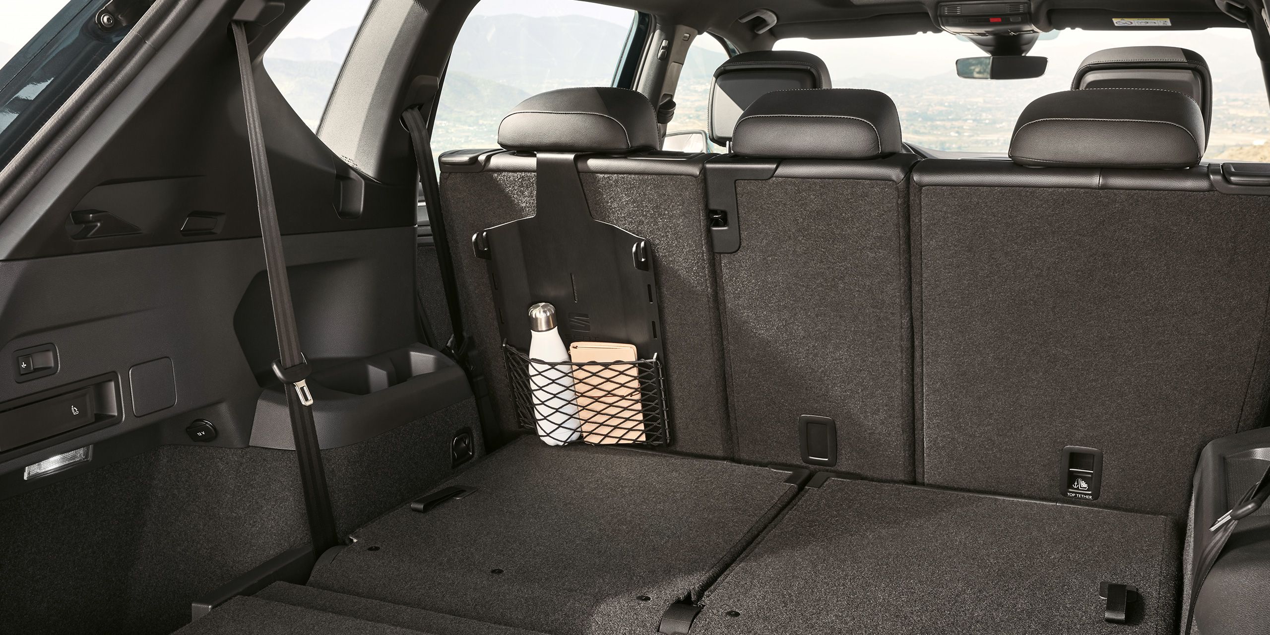 Blick auf ein in einem Netz im Kofferraum eines SEAT Tarraco befestigtes Tablet und eine Flasche. 