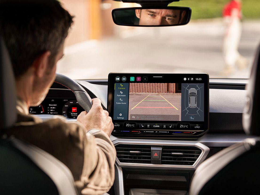 Ein Mann blickt während des Parkens auf das Infotainment Display mit dem Park Assistenten eines SEAT Leon SP Kombi.