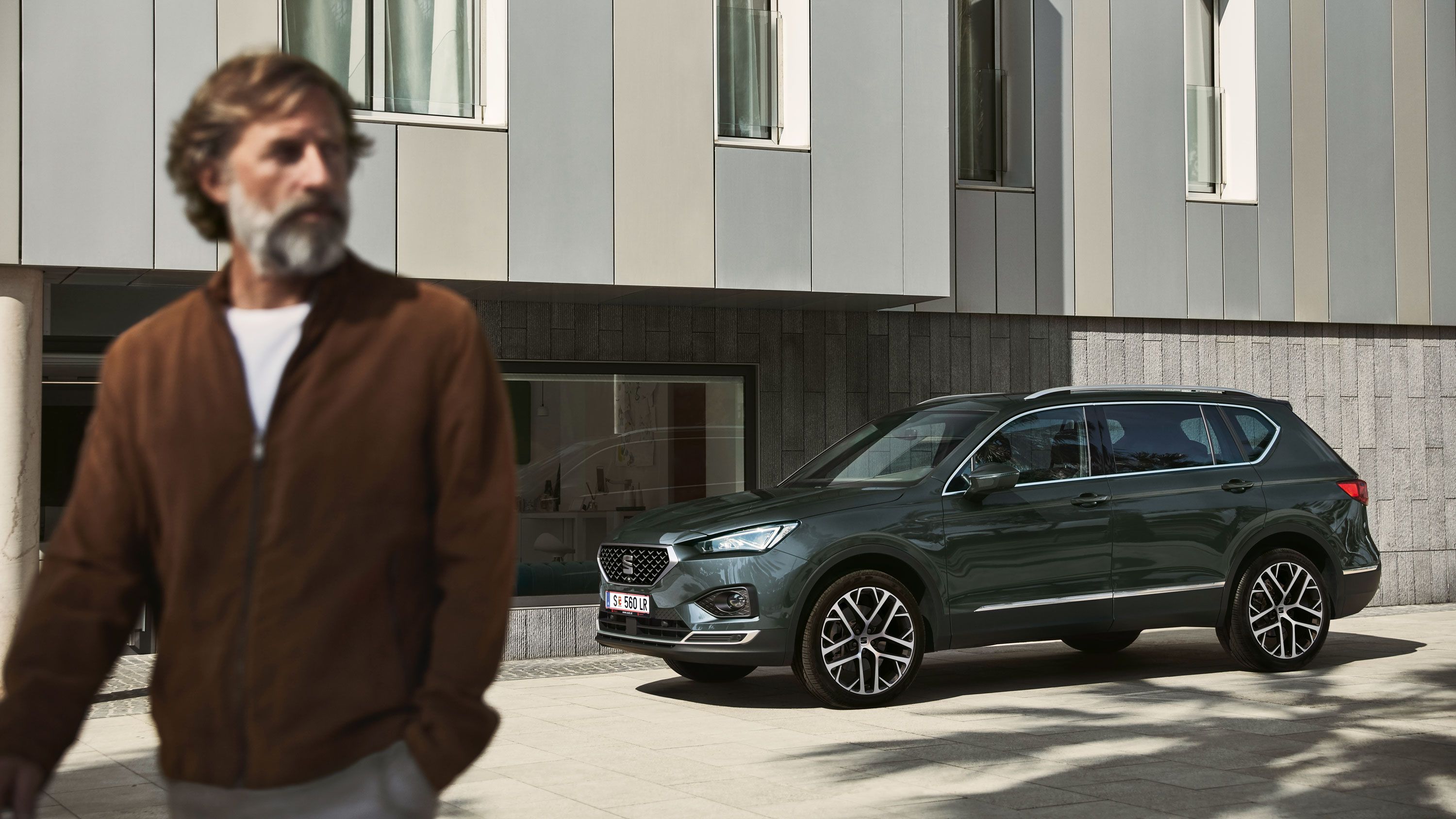 Ein SEAT Tarraco parkt am Straßenrand und ein Mann geht von dem Fahrzeug fort.